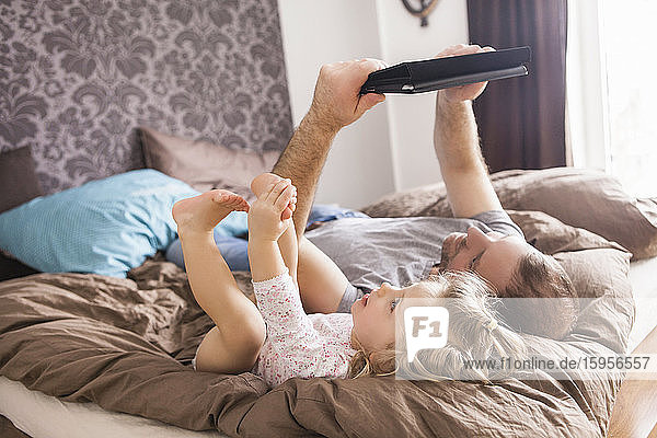 Vater und Tochter betrachten die im Bett liegende Tablette
