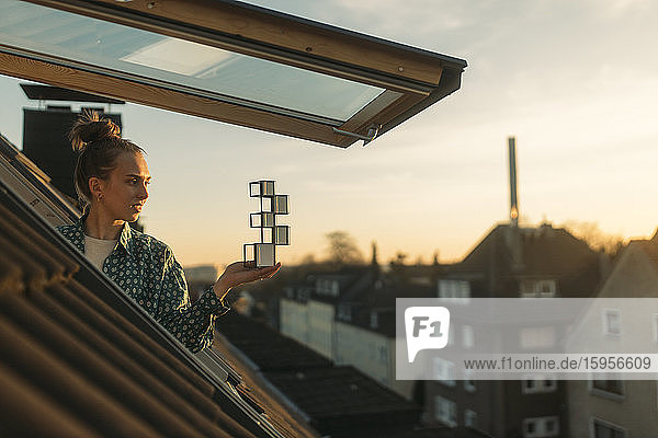Young woman holding design at the window in the evening
