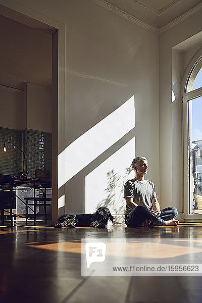Reifer Mann sitzt zu Hause auf dem Boden und meditiert