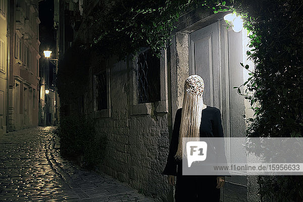 Schwarz gekleidete Frau mit gehäkeltem weißem Kopfschmuck mit Fransen bei Nacht  Rovinj  Kroatien