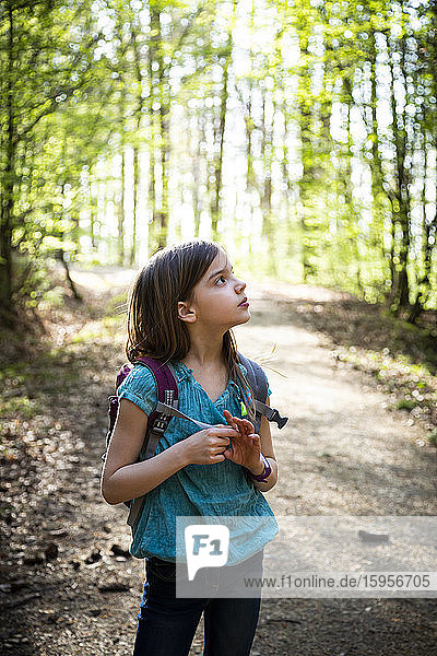 Bildnis eines Mädchens mit Rucksack auf einem Waldweg stehend