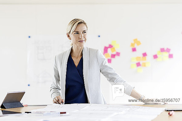 Blond businesswoman in conference room with adhesive notes at whiteboard
