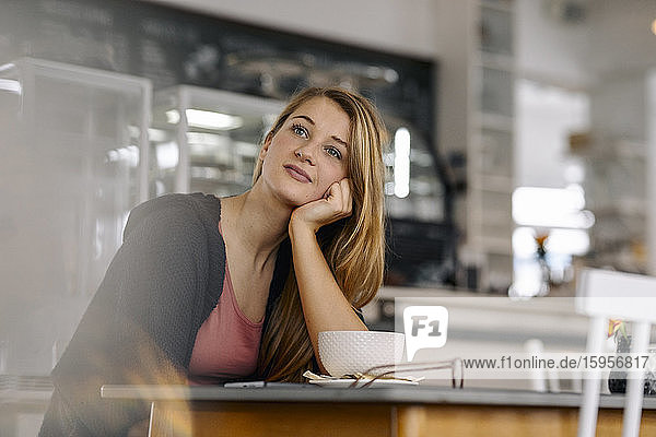 Porträt einer tagträumenden jungen Frau in einem Cafe