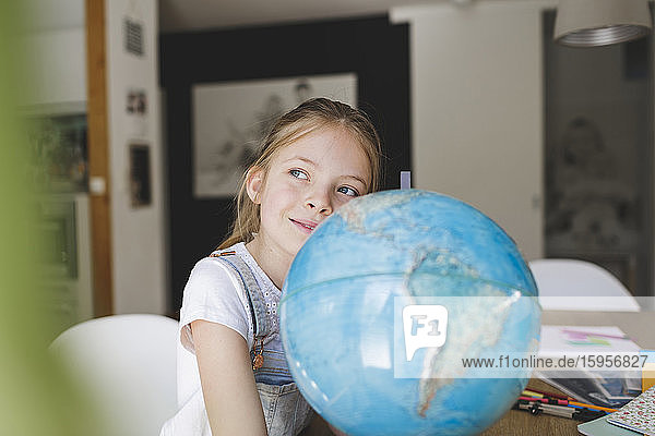 Porträt eines selbstbewussten Mädchens mit Globus zu Hause  das in die Ferne schaut