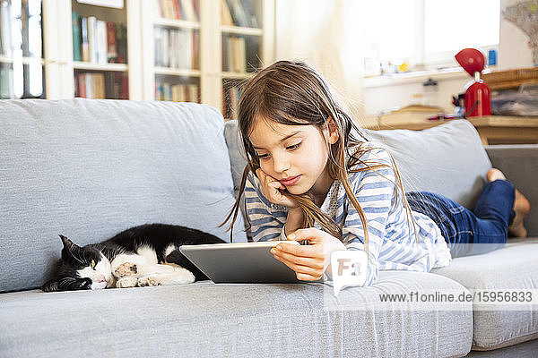 Porträt eines auf einer Couch liegenden Mädchens mit digitalem Tablett