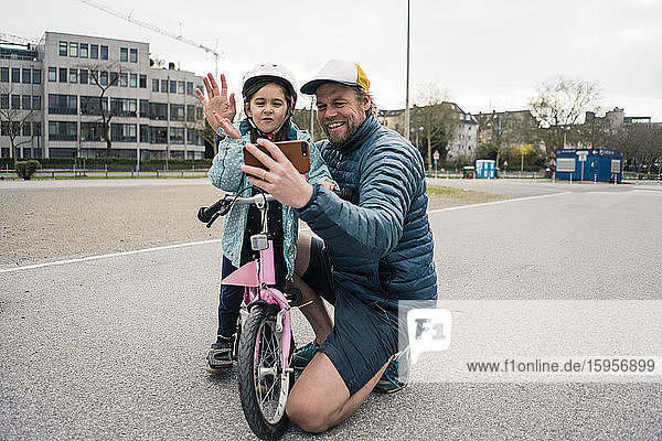 Glückliche Vater und Tochter mit dem Fahrrad beim Selbstfahren