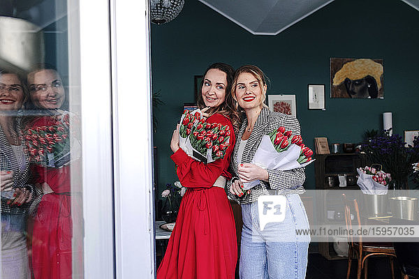 Zwei Frauen halten Sträuße mit roten Tulpen in einem Blumenladen