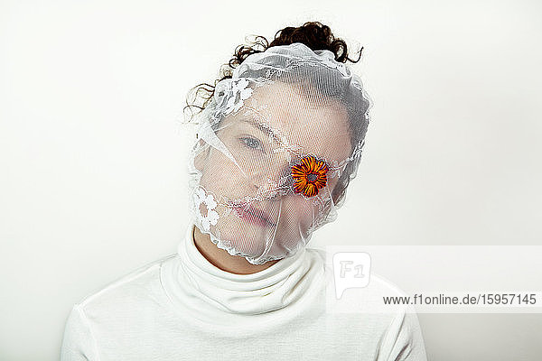 Bildnis einer jungen Frau mit weißem Schleier und einer Blume  die ein Auge bedeckt