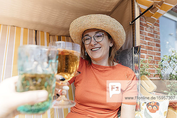 Porträt einer glücklichen reifen Frau auf der Terrasse  die mit einem Glas Limonade anstößt