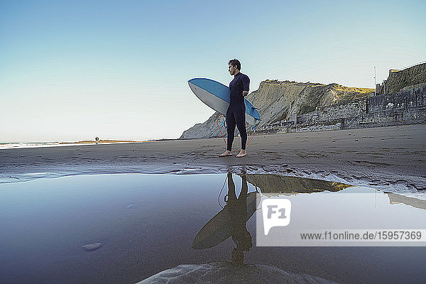 Behinderter Surfer mit Surfbrett am Strand stehend