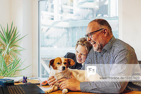 Happy father and son at home with dog on desk