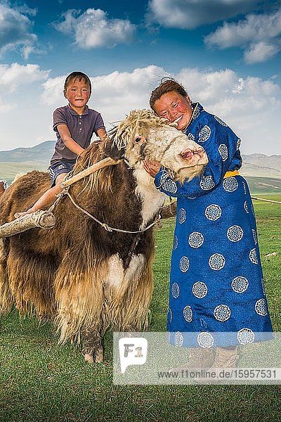 Nomadische Frau umarmt den Kopf eines Yaks  ein Junge sitzt auf dem Rücken des Yaks  Provinz Uvurkhangai  Mongolei  Asien