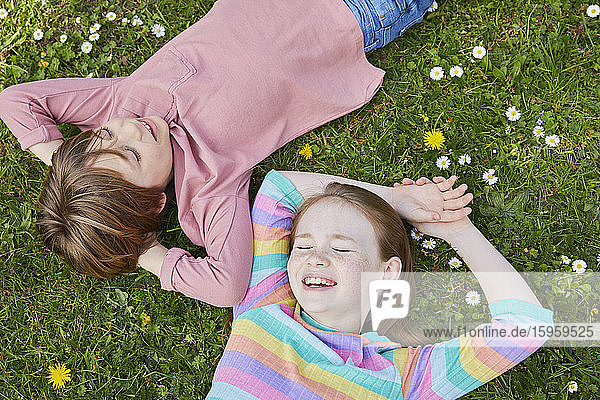 Hochwinkelaufnahme eines Jungen und eines Mädchens die auf einer Frühlingswiese liegen.