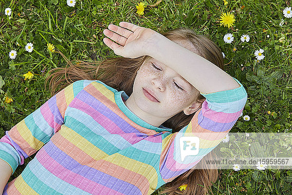 High angle view of girl wearing striped top lying on a spring meadow.