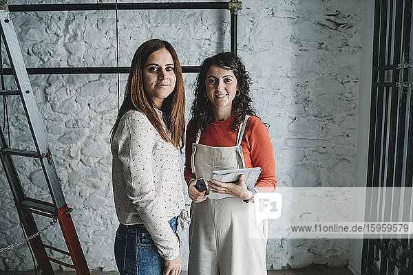 Two mid adult women preparing their new shop  portrait