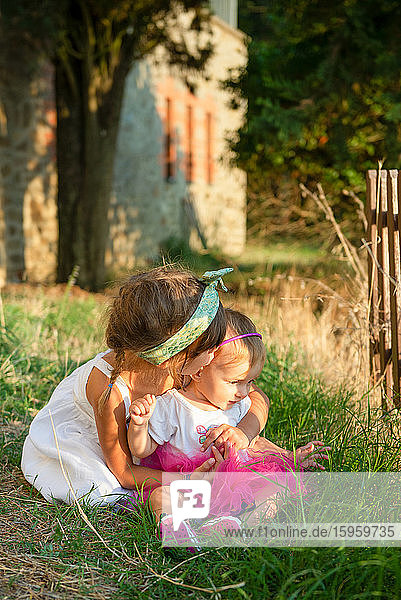Portrait of two girls sitting in a sunny garden.