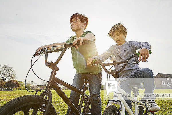 Zwei Jungen fahren mit ihren BMX-Rädern in einem Park.