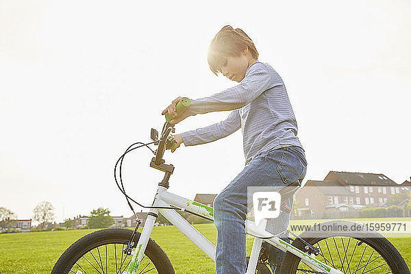 Brünetter Junge fährt mit seinem BMX-Rad in einem Park.