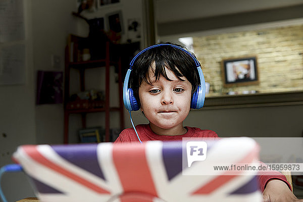Ein fünfjähriger Junge mit blauen Kopfhörern bei einer interaktiven Lernsitzung  Heimunterricht.