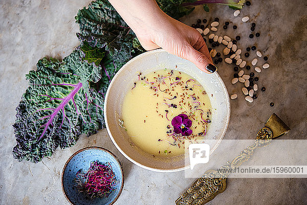 Speisen auf einem Tisch in einem veganen Café eine Schüssel mit frischen Kräutern und essbaren Blumen Grünkohlblätter und rohe Hülsenfrüchte und Nüsse.