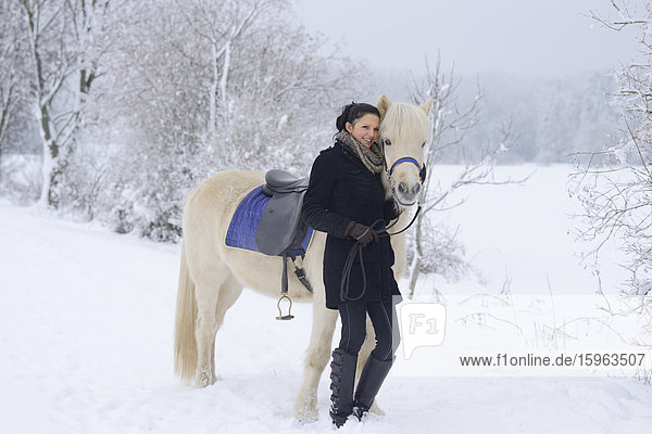 Young woman with horse in snow