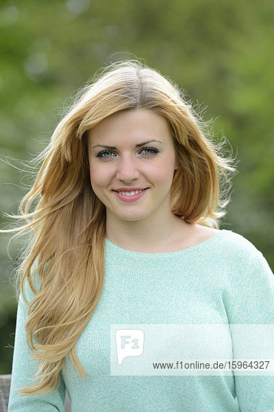 Lächelnde blonde junge Frau im Freien  Portrait