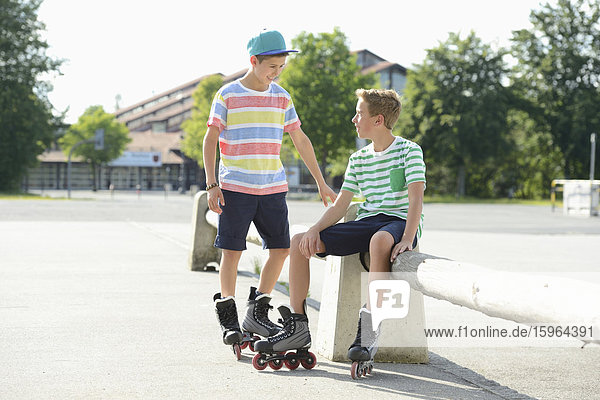 Two boys with in-line skates on a sports place