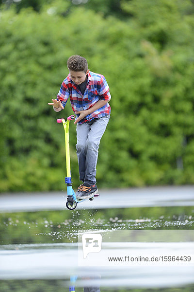 Junge mit Kickboard an einem regnerischen Tag