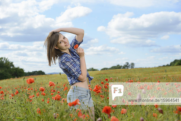 Young woman standing in a poppy field