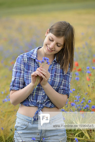 Young woman standing in a cornflower field
