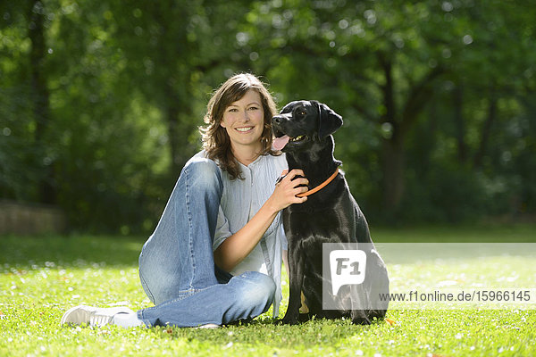 Frau mit einem schwarzen Labrador auf einer Wiese  Bayern  Deutschland  Europa