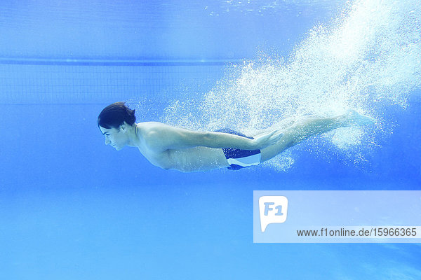 Mann schwimmt unter Wasser in einem Freibad