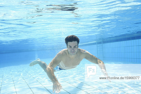 Mann schwimmt unter Wasser in einem Freibad