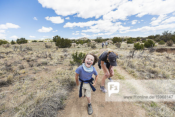 6-jähriger Junge  der mit seiner älteren Schwester auf einem Wanderweg läuft  Galisteo Basin  NM.