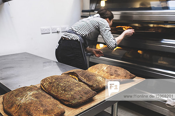 Eine handwerkliche Bäckerei  die spezielles Sauerteigbrot herstellt  ein Bäcker  der die gebackenen Laibe kontrolliert.