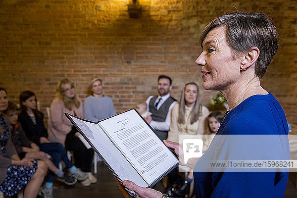 Celebrant performing naming ceremony for parents and their baby daughter in an historic barn.