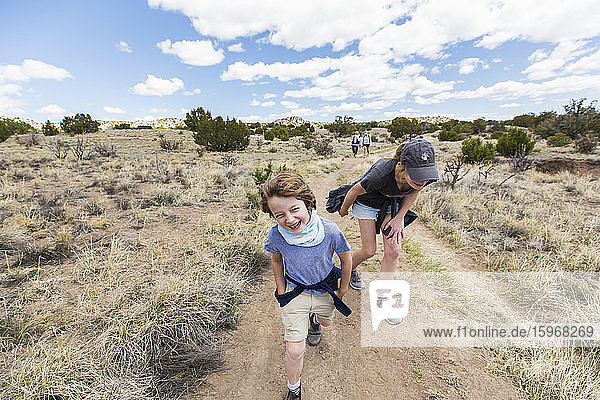 6 year old boy running on hiking trail with older sister  Galisteo Basin  NM.