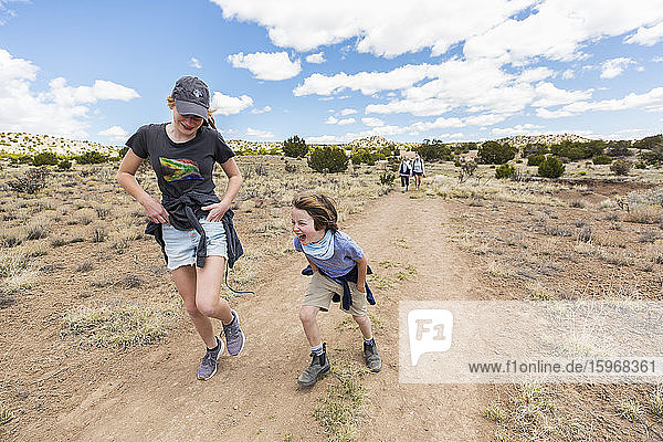 6 year old boy running on hiking trail with older sister  Galisteo Basin  NM.