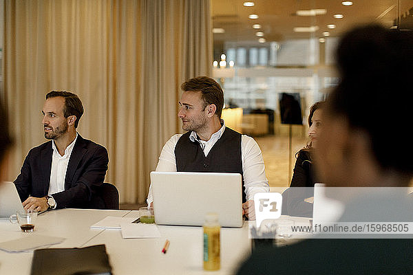 Männliche und weibliche Geschäftsleute mit Laptop bei Besprechung im Büro