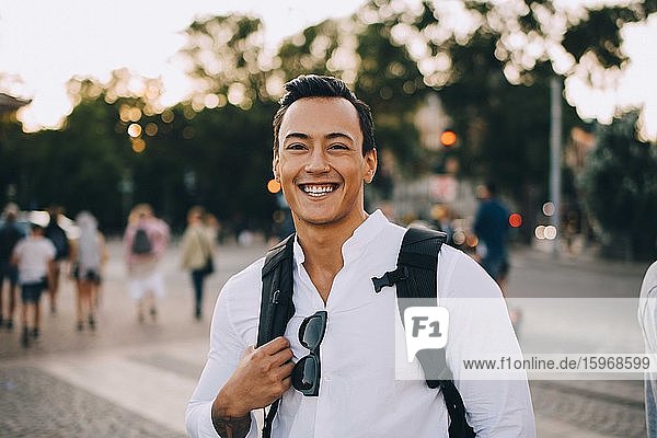 Portrait of smiling young man with bag in city