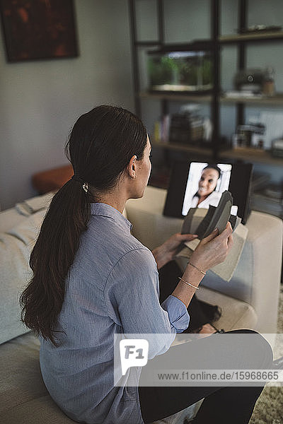 Seitenansicht des Architekten mit Stoffmuster auf Videokonferenz über Laptop bei der Arbeit zu Hause