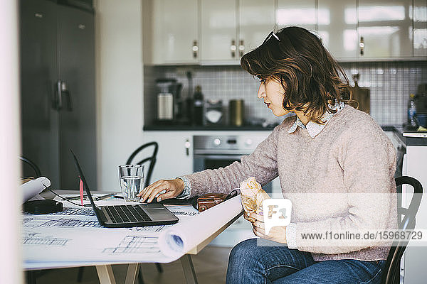 Woman in kitchen working from home having lunch