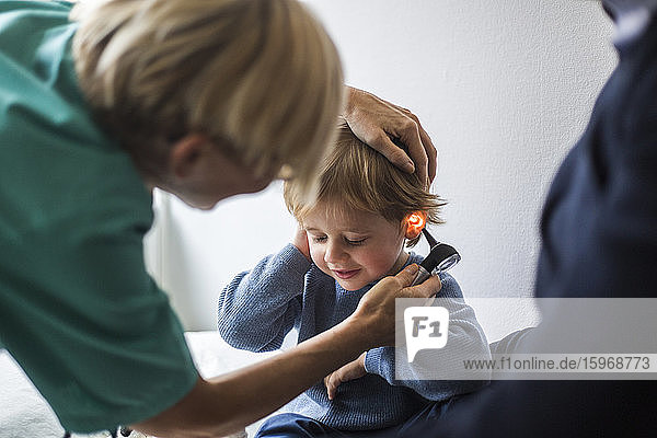 Ärztin untersucht im Krankenhaus das Ohr des Jungen mit dem Otoskop
