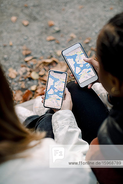 Weitwinkelansicht von Teenager-Mädchen  die über eine App auf Smartphones nach Freunden suchen