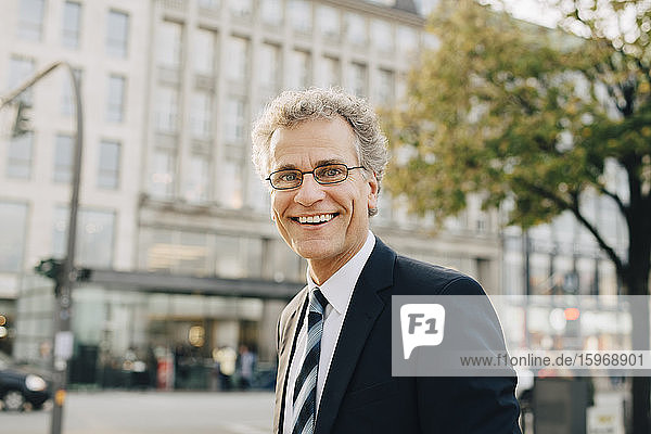 Portrait of smiling businessman wearing suit while standing in city