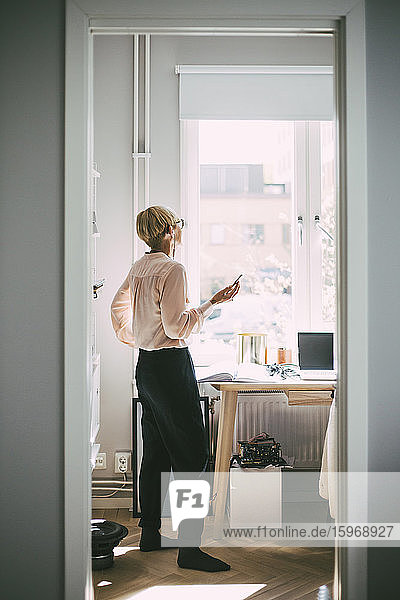Woman standing in home office talking on the phone