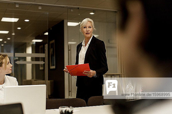 Businesswoman discussing with male and female colleagues in meeting at workplace