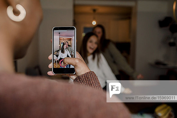 Mädchen mit Smartphone filmt Teenager-Freunde  die zu Hause im Wohnzimmer tanzen