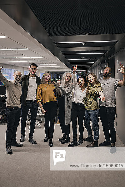 Portrait of business team cheering while standing together at open office space