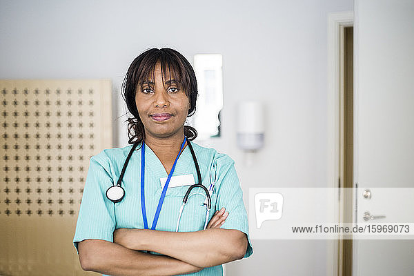 Porträt einer reifen Gesundheitshelferin mit verschränkten Armen stehend in der Klinik
